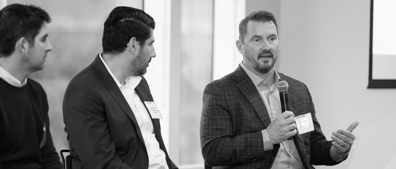 Kevin Jones, at right, speaking into a microphone on a panel at LLR Collaborate