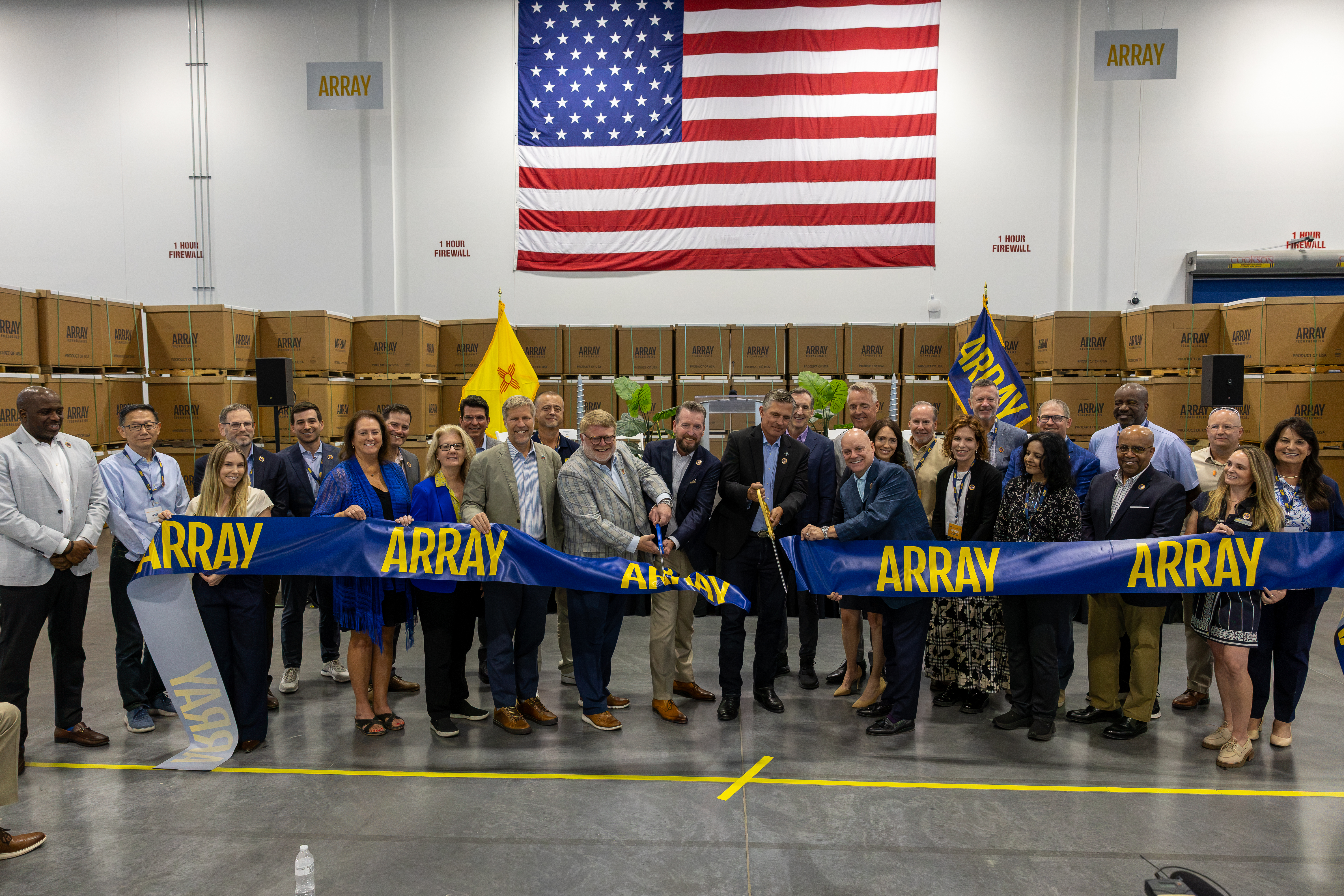 Array staff, executives and public officials cut a blue and yellow ribbon inside the new Albuquerque manufacturing facility