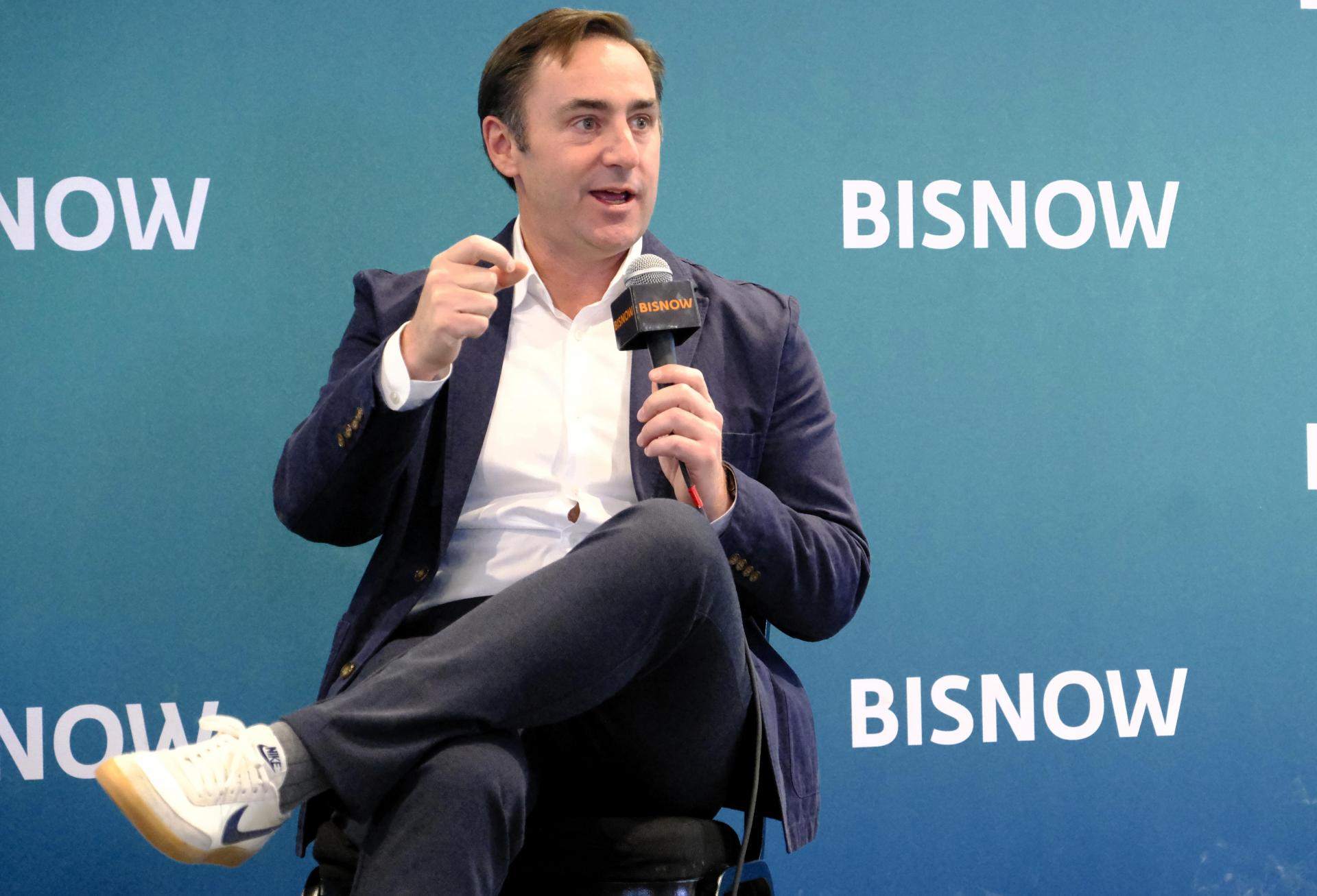 Kevin McCrain holding a microphone while speaking at Bisnow’s Chicago summit in May 2026.
