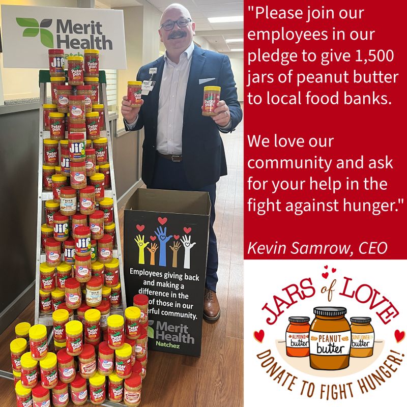 Kevin Samrow holding jars beside a tower of peanut butter collected for the 2024 Jars of Love drive