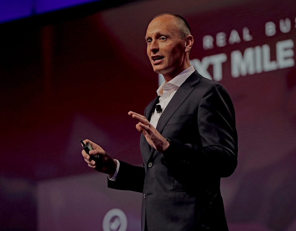 Kevin Samuelson speaking on an Infor stage, holding a presentation clicker