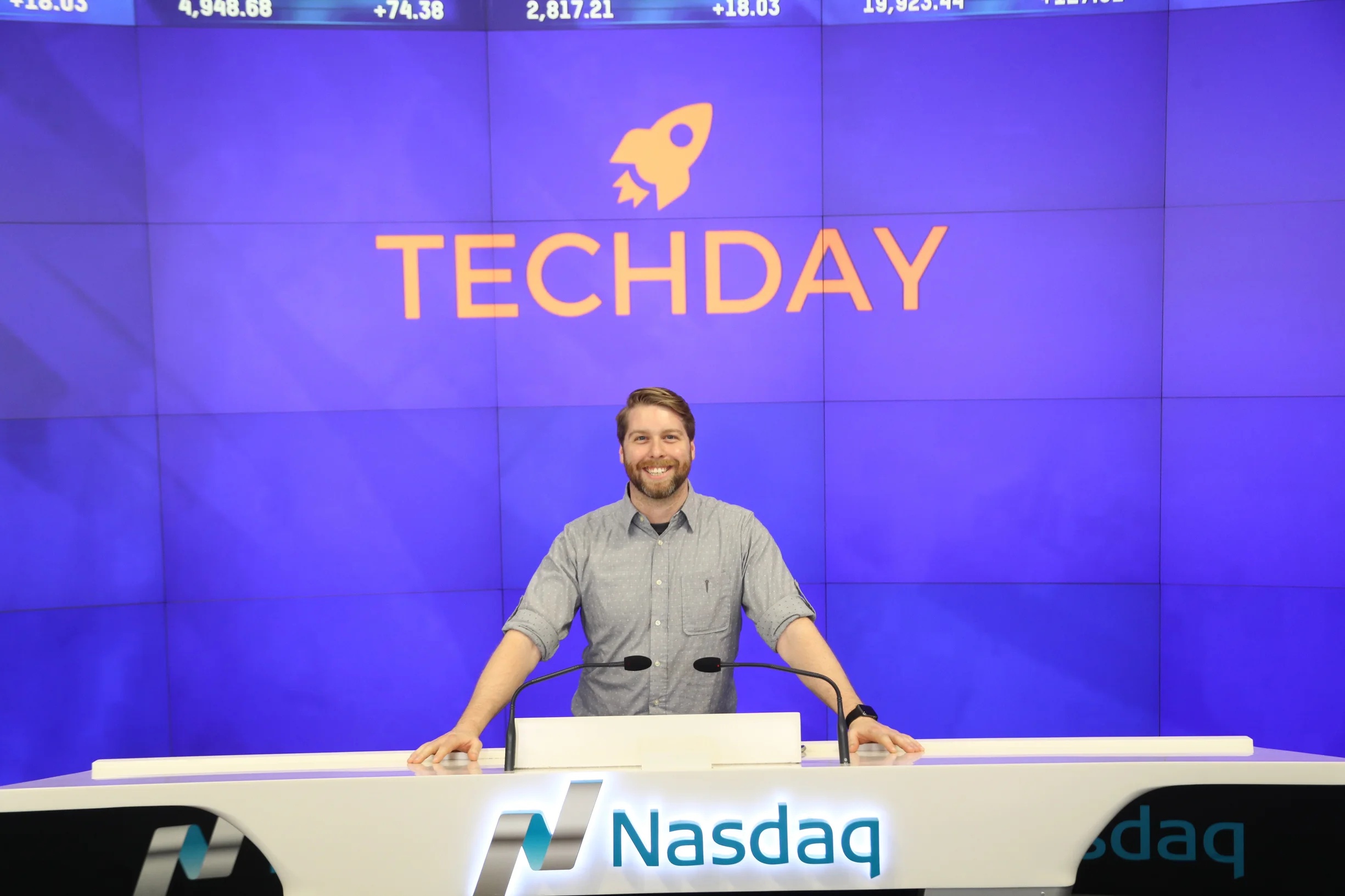 Kevin Siskar standing behind the Nasdaq desk beneath a large TechDay backdrop