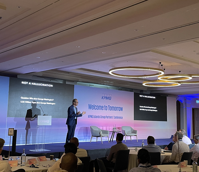 Kevin Surace presenting on a conference stage, with the audience seated in front of him