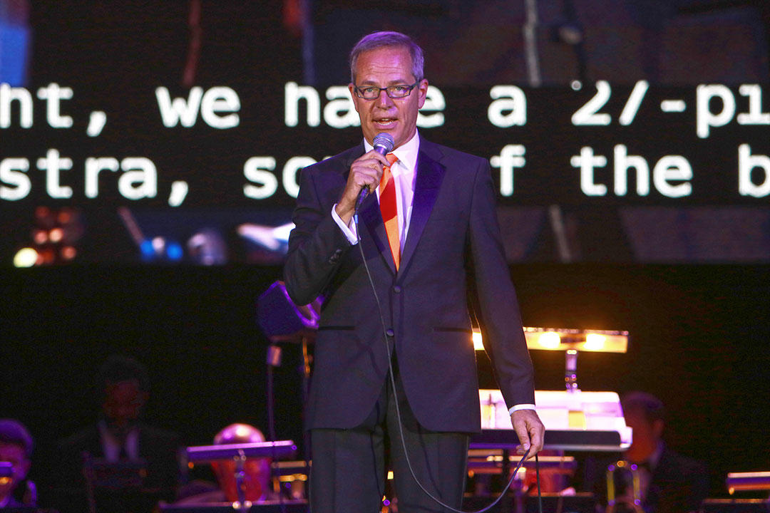 Kevin Surace holding a microphone while serving as master of ceremonies at an RIT gala