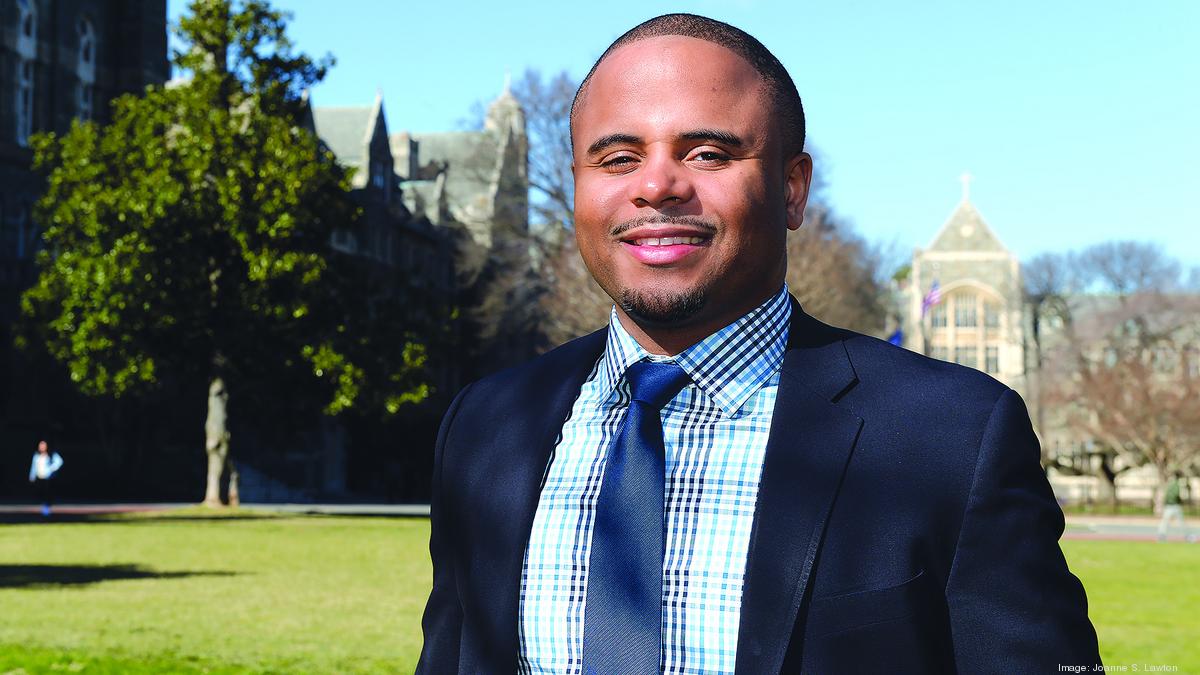 Kevin Turpin outdoors in a suit and checked shirt, with university buildings behind him.
