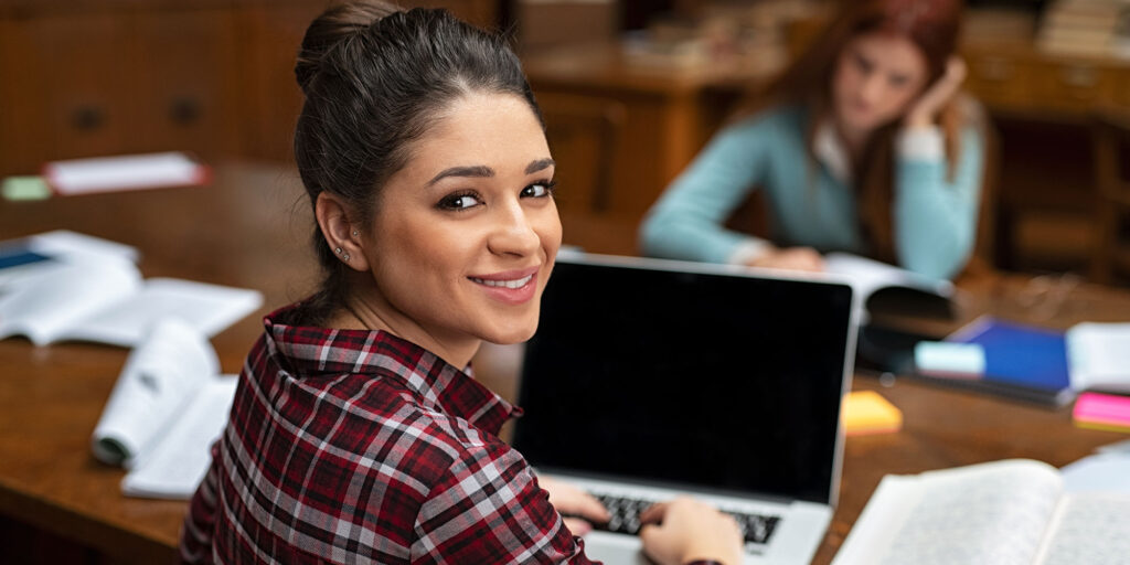 Illustrative photograph of learners working with laptops and study materials