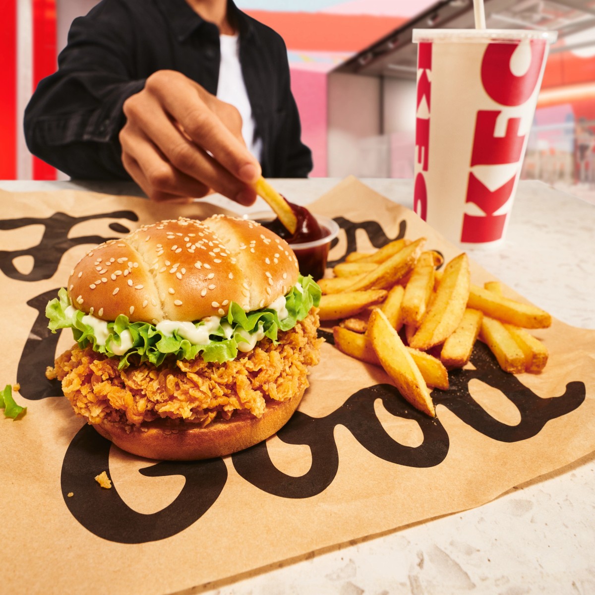 KFC chicken burger with fries, a drink and barbecue dip on branded packaging