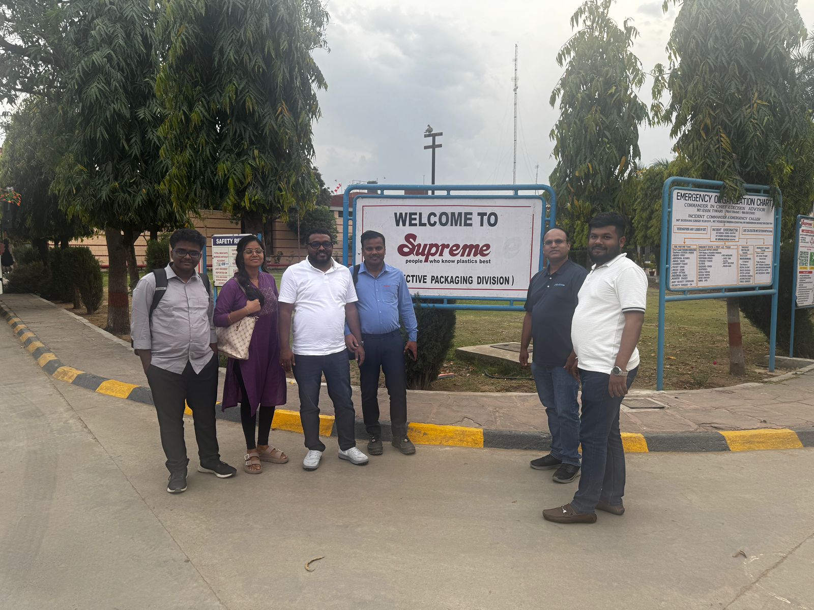 Six visitors beside the Supreme Industries facility entrance sign