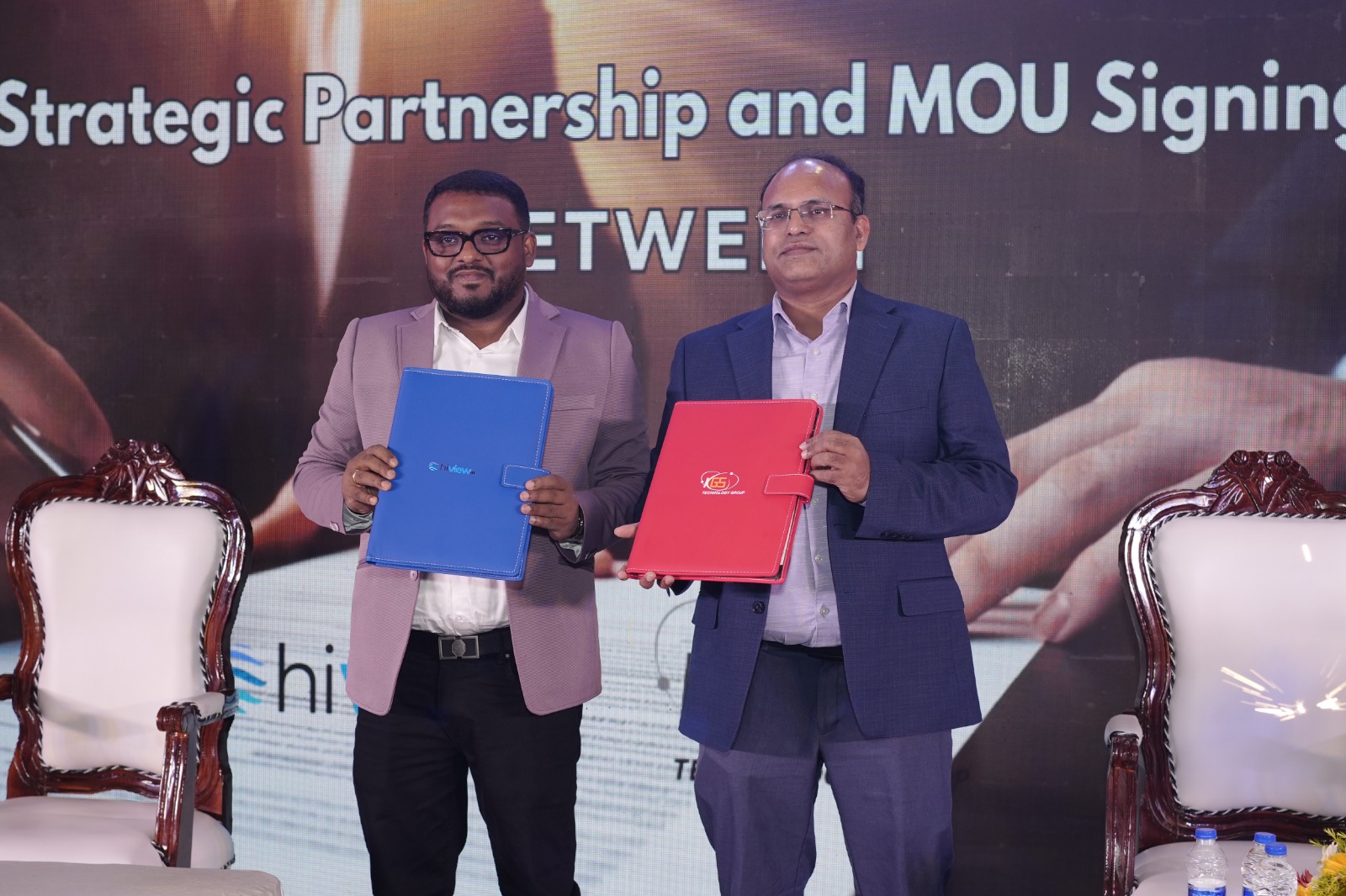 Two representatives holding HiView.ai and KGS agreement folders at a partnership event