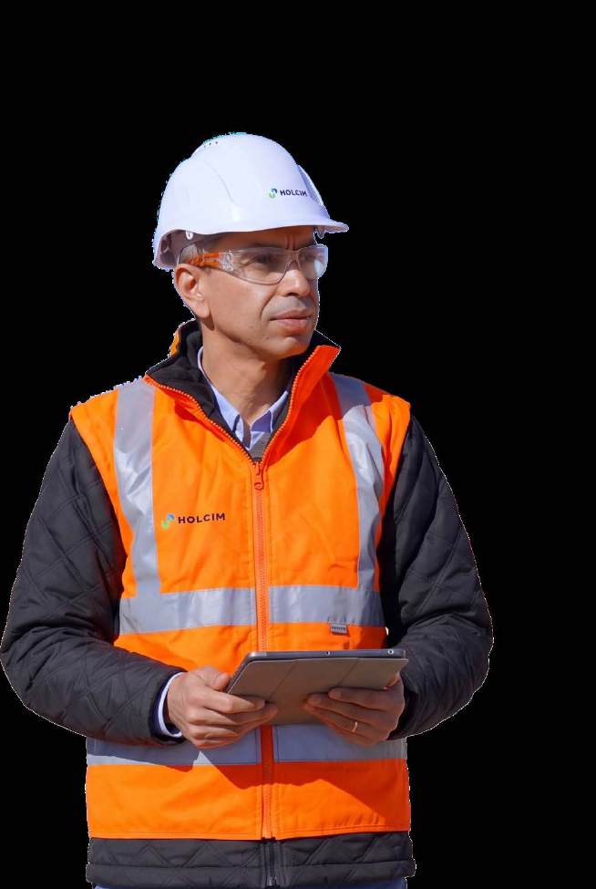 Khalid Samaka wearing a Holcim hard hat and orange work vest, holding a tablet