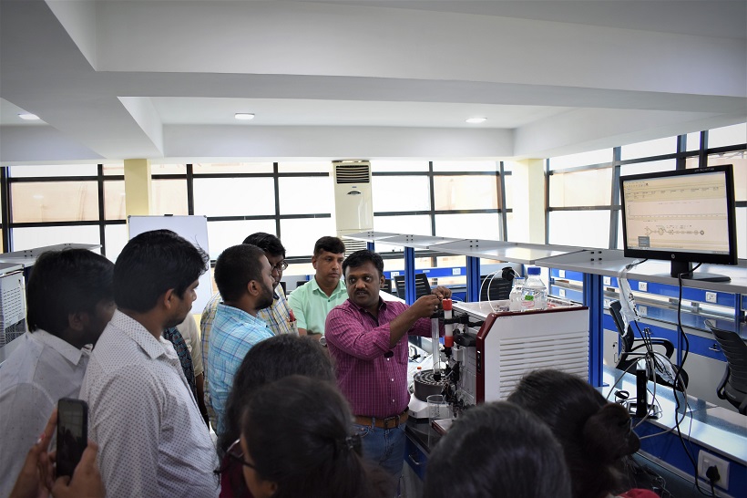 Participants gather around bioprocess equipment during hands-on training at KIIT-TBI