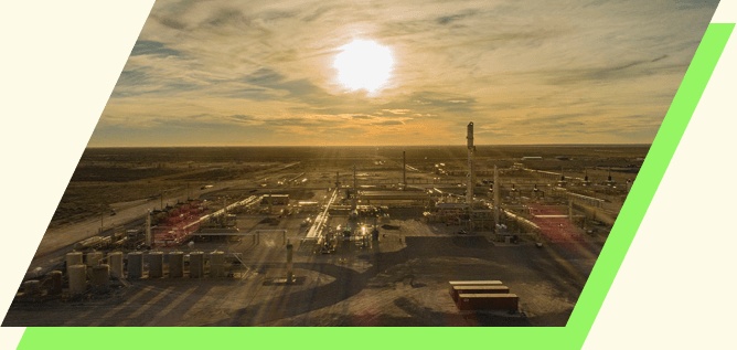 Sunrise above a Kinetik processing plant, with tanks, pipes and towers spread across the foreground