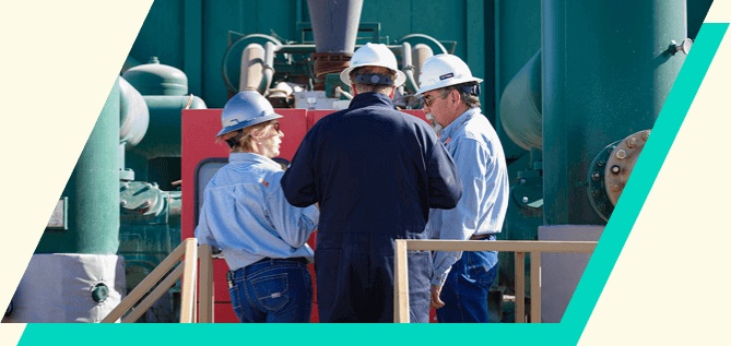 Kinetik employees standing among equipment at the West Mustang facility