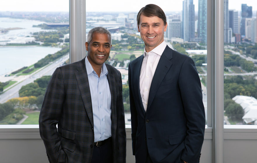 Vistria co-founders Marty Nesbitt, left, and Kip Kirkpatrick, right, with Chicago behind them