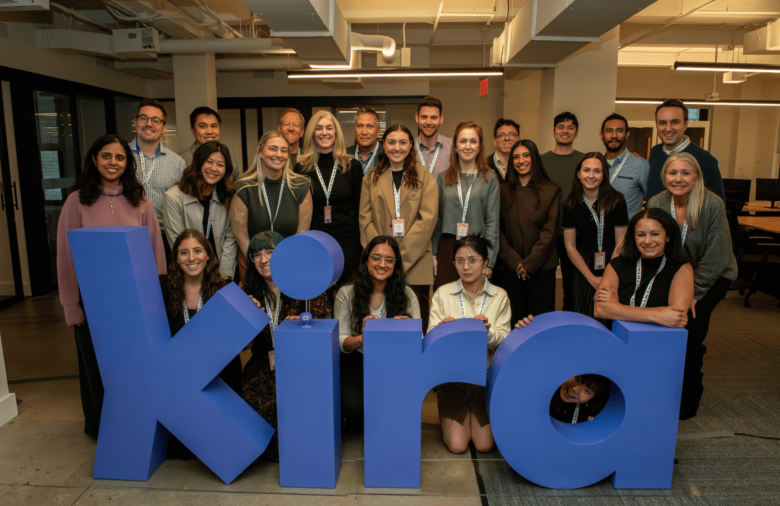 The Kira team gathered behind large blue letters spelling Kira