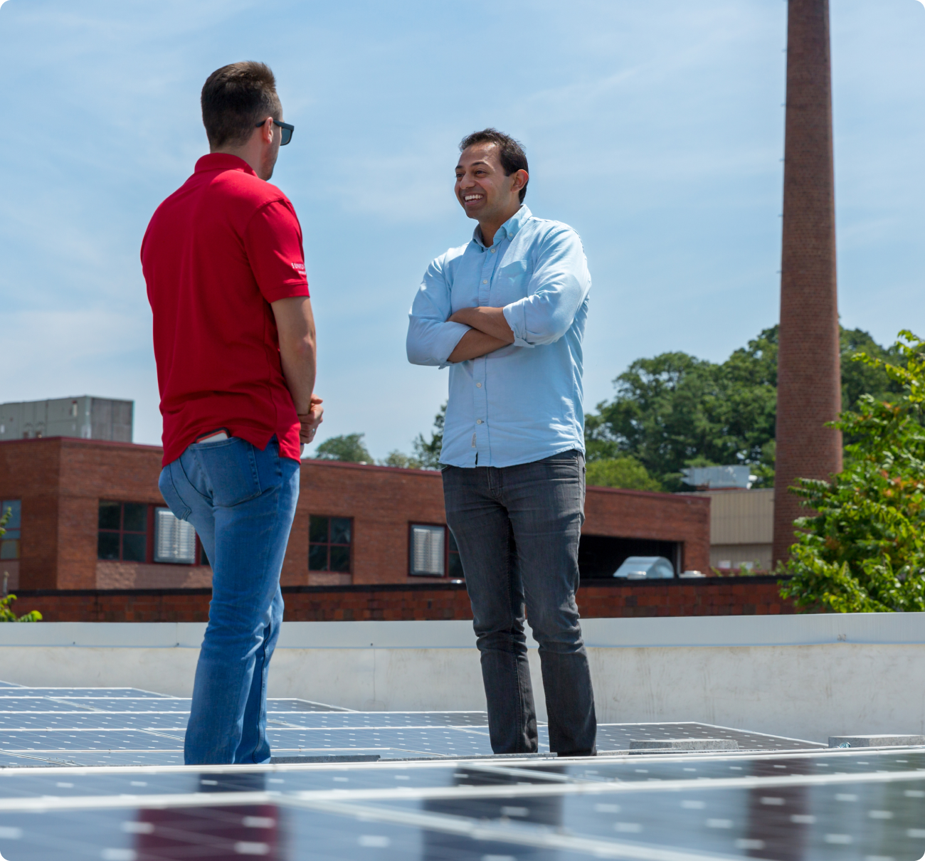 Kiran Bhatraju talking with another person beside rooftop solar panels