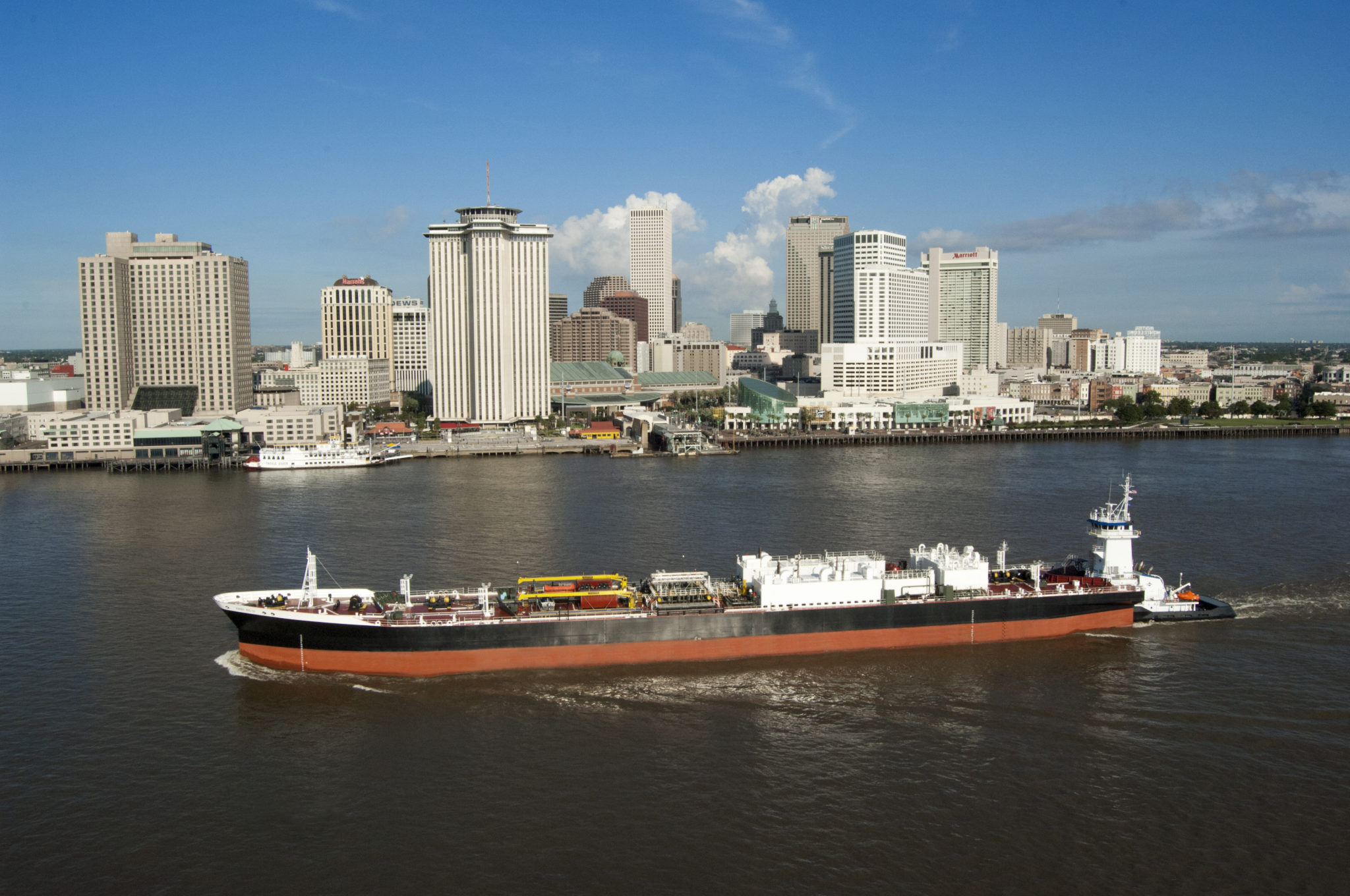 A Kirby tank barge and tug moving along the river beside downtown New Orleans