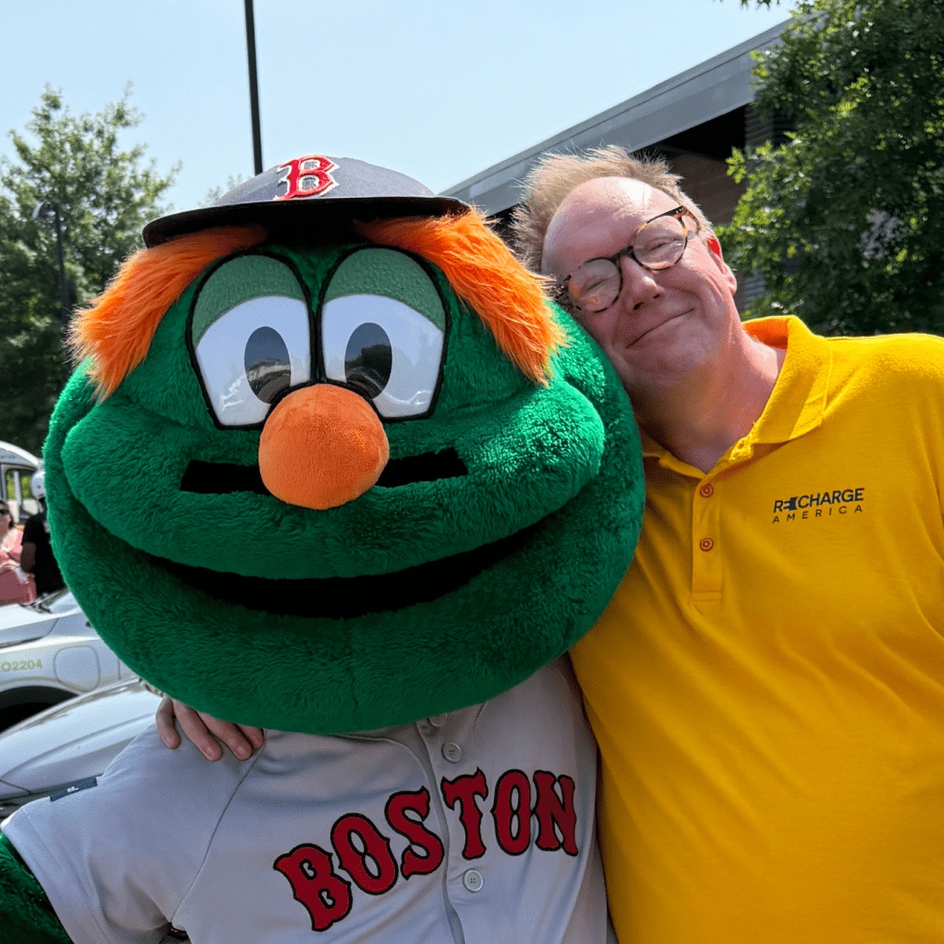 Kirk Brown in a yellow Recharge America shirt beside a Boston Red Sox mascot