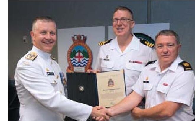 Commander Scott Godin and Chief Petty Officer 2nd Class Kirk Peck accepting a Bravo Zulu award with a senior naval officer in 2018