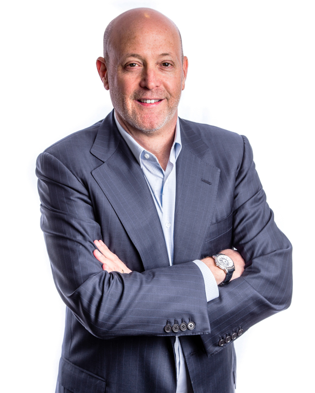 Kirk Posmantur in a blue jacket, standing with his arms folded