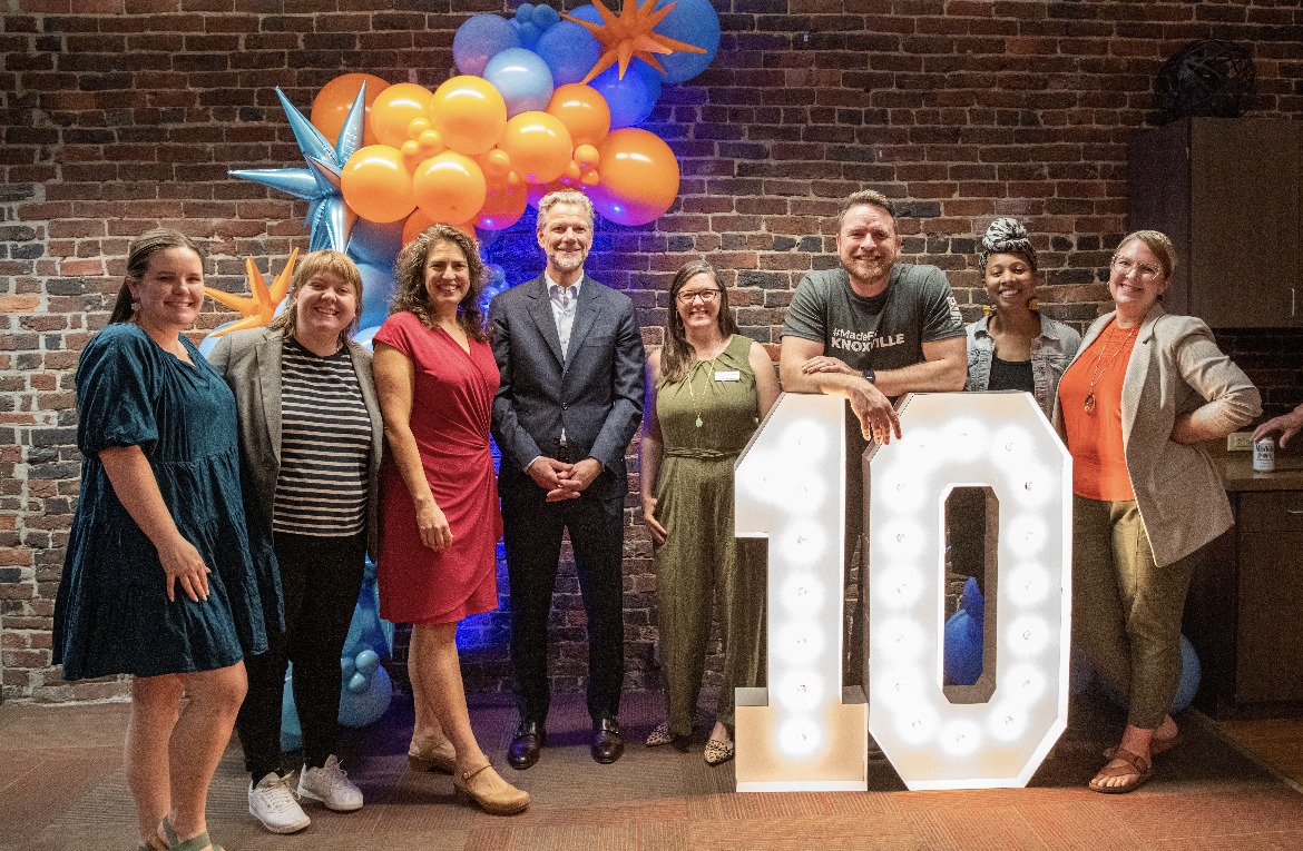 A group gathered beside illuminated number ten decorations at KEC’s 2023 anniversary celebration