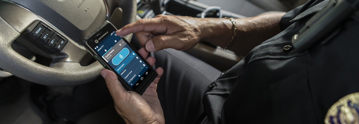 A field worker using the Kodiak push-to-talk application on a rugged Motorola phone inside a vehicle