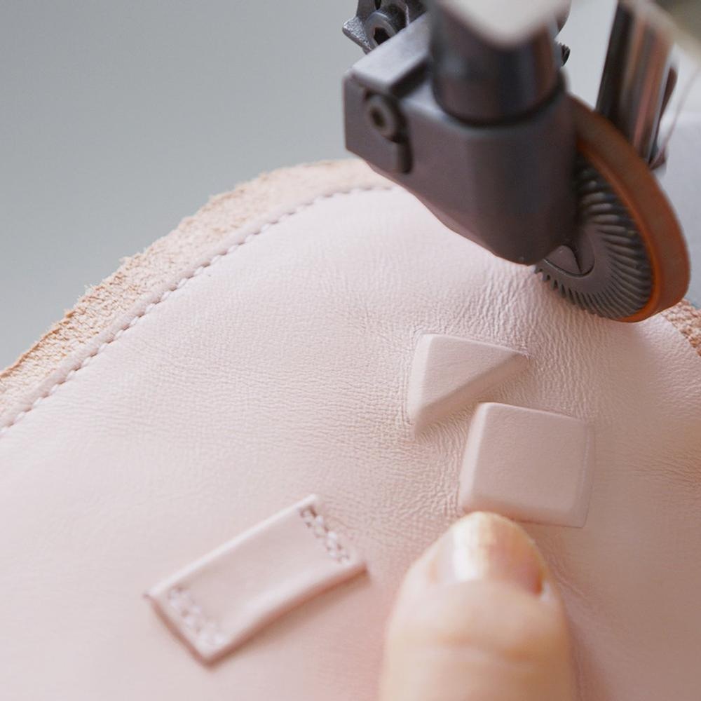 An artisan stitching a white Koio sneaker upper in Italy