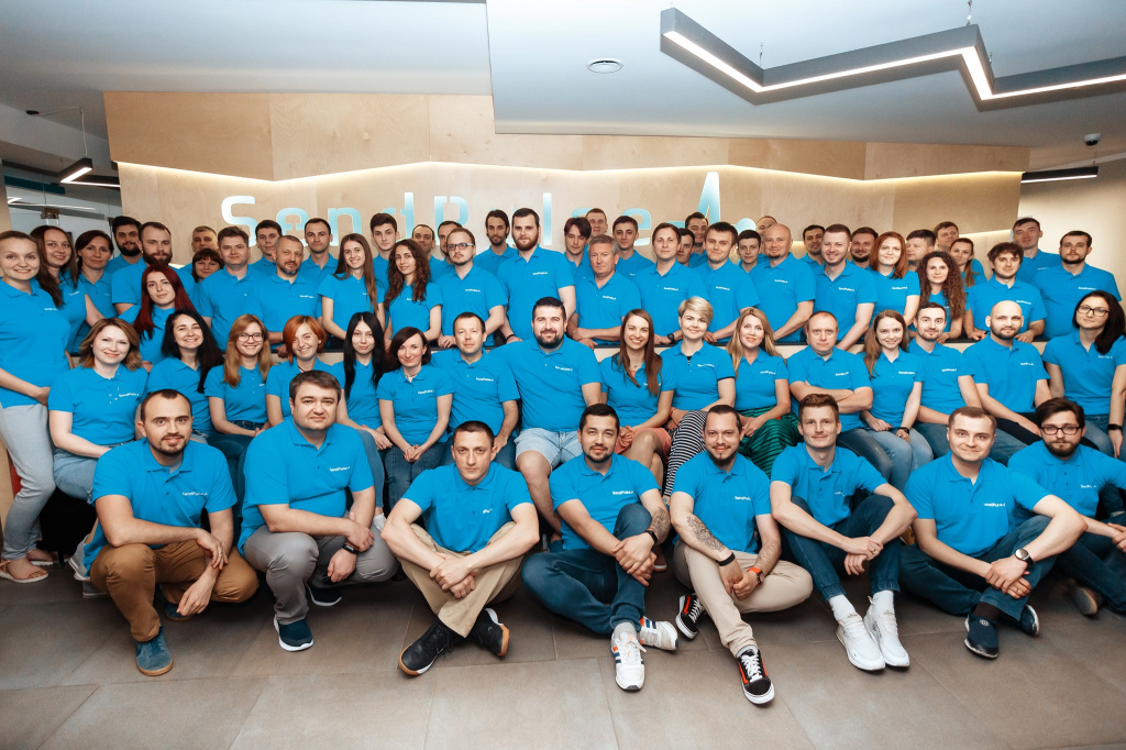 Makarov seated among SendPulse colleagues wearing blue company shirts