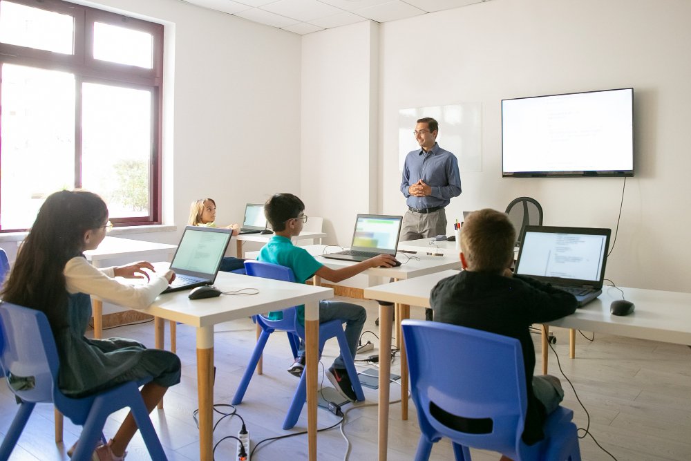 A teacher and students working with laptops in a classroom