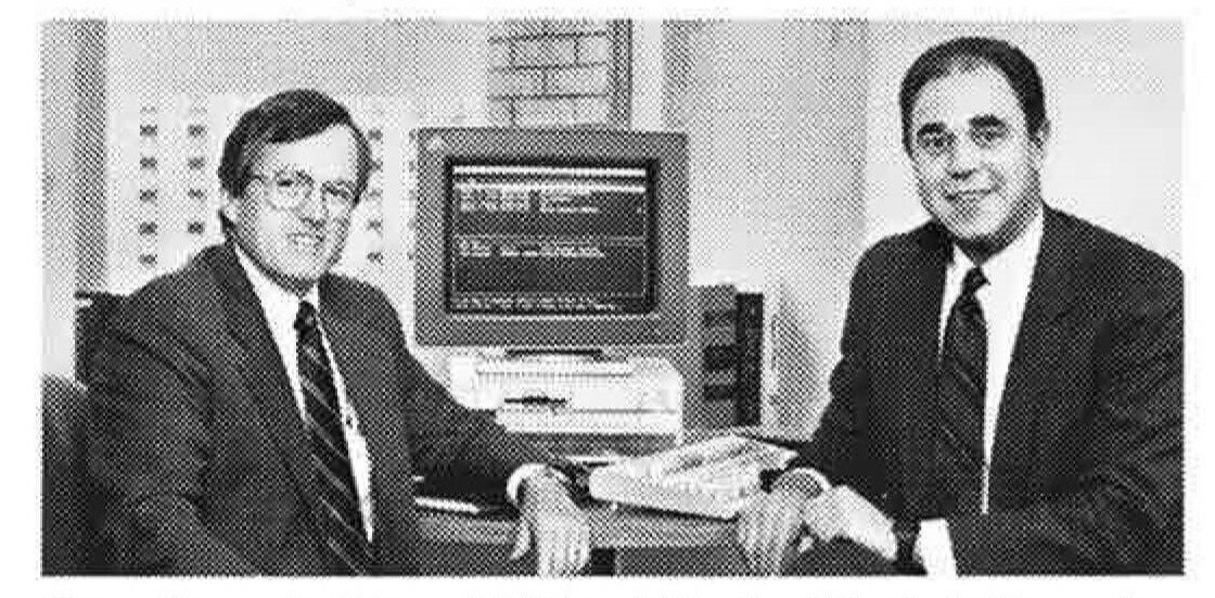 Archival black-and-white photograph of founders Peter Kennedy and Michael Kraft beside a desktop computer