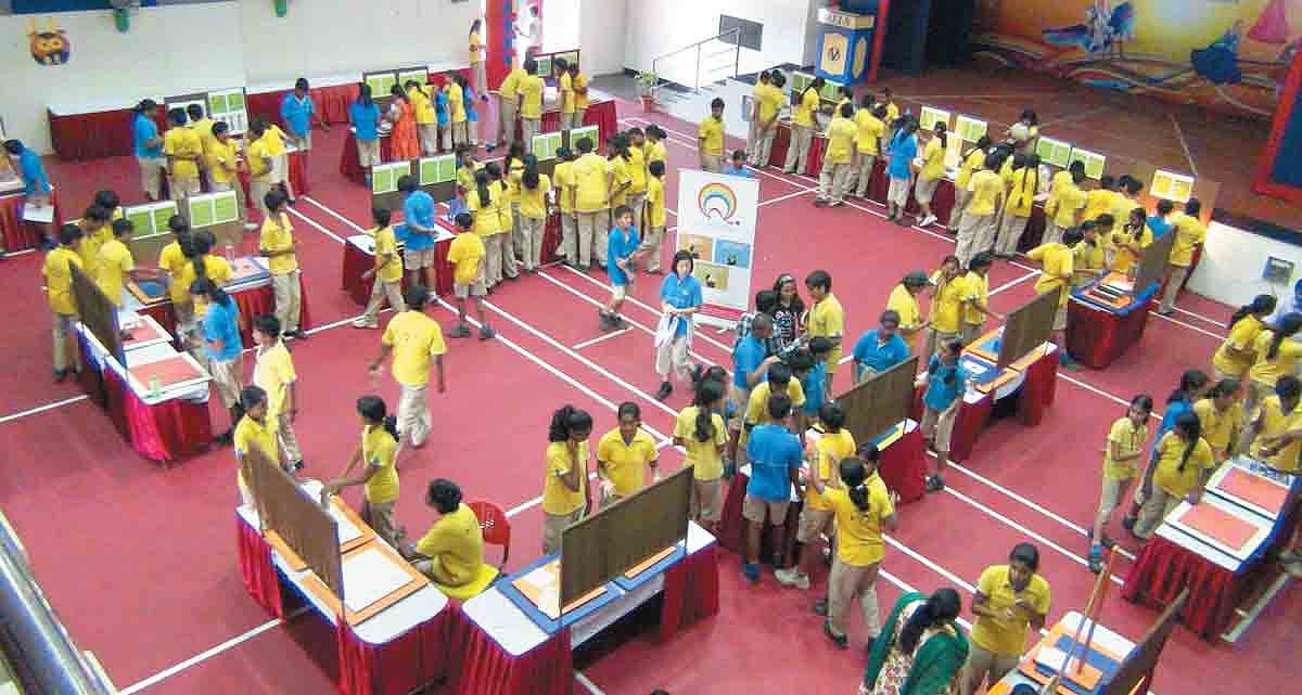 Students gather around working exhibits at a QED science event.