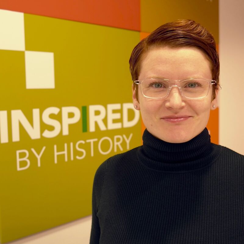 Kristen Gwinn-Becker standing before a colorful Inspired by History backdrop