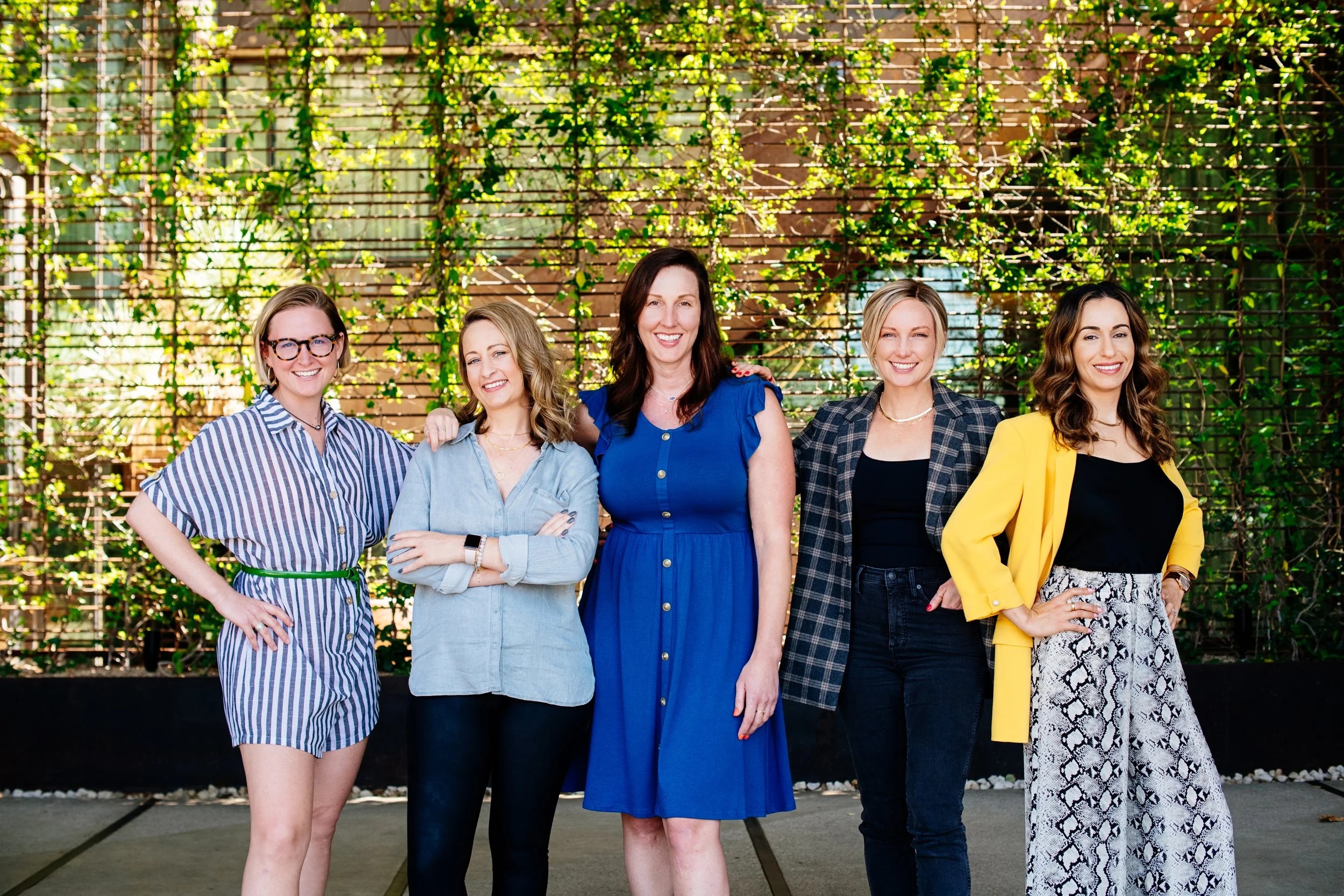 Kristen Ostro, center in a blue dress, standing with four colleagues outdoors
