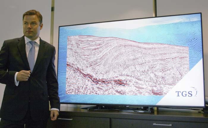 Kristian Johansen standing beside a display of layered seismic data