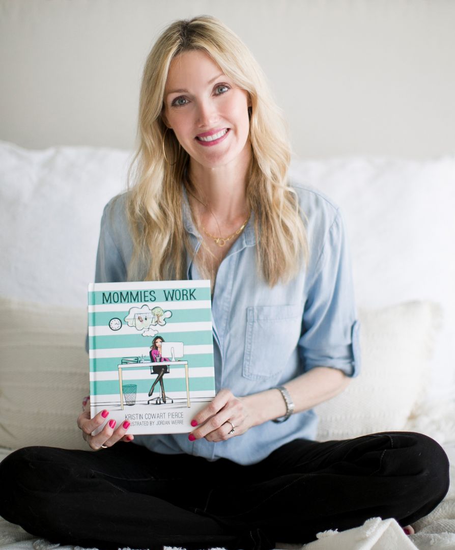 Kristin Cowart Pierce seated with a copy of her children's book Mommies Work