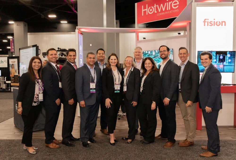 Hotwire Communications colleagues gathered at a Hotwire and Fision exhibition booth