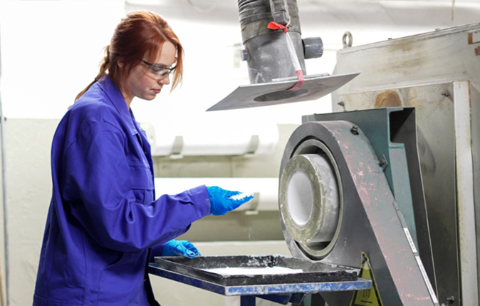 A KRONOS laboratory worker examining material beside testing equipment