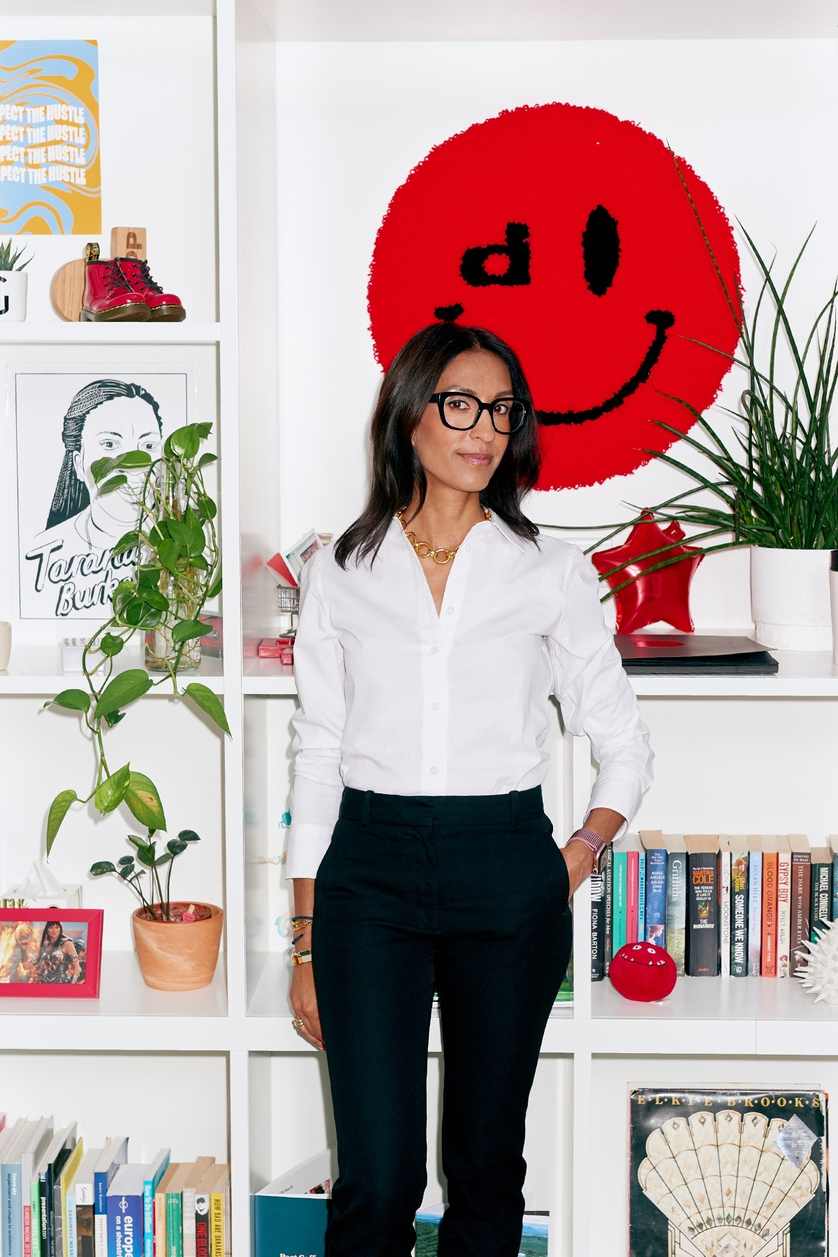 Kruti Patel Goyal standing beside shelves, plants and a red smiley artwork during her Depop tenure