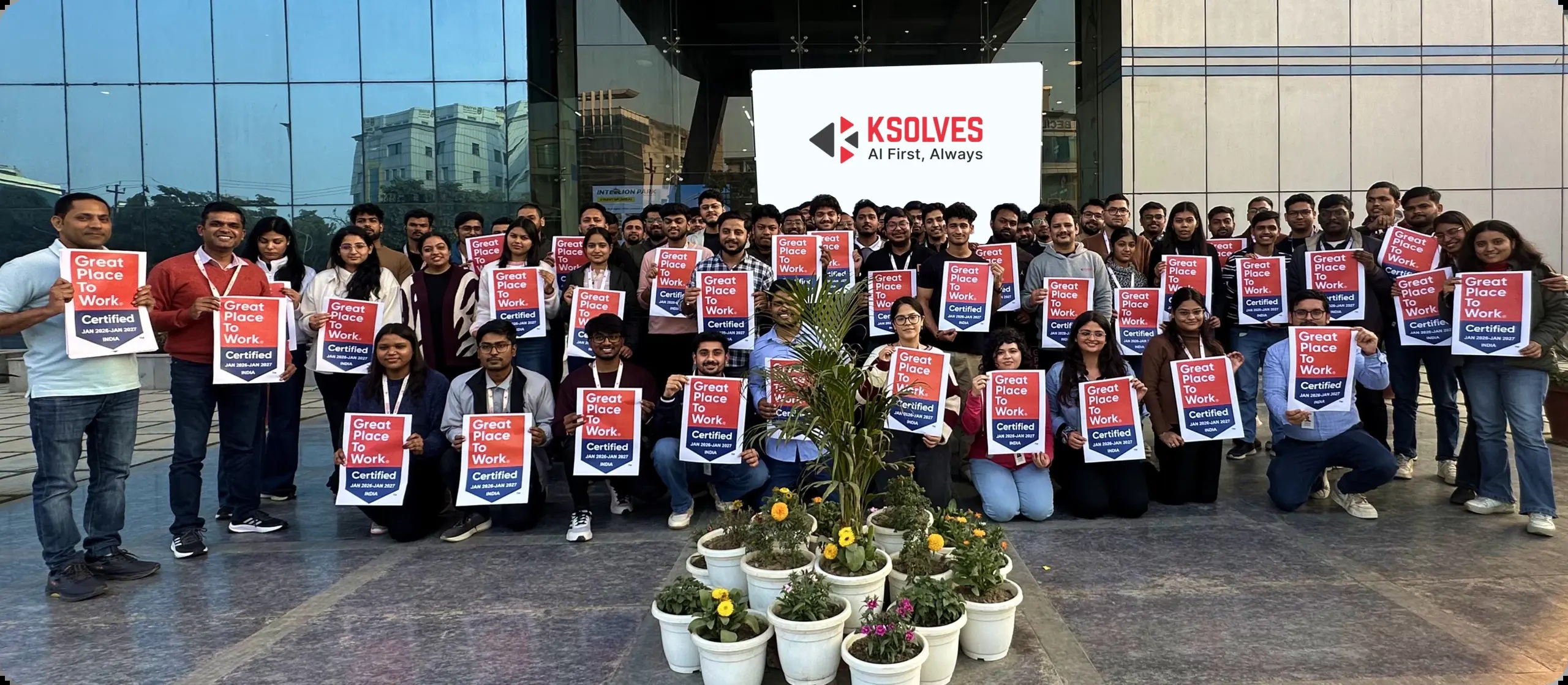 Ksolves employees gathered outside their office holding Great Place to Work certification signs