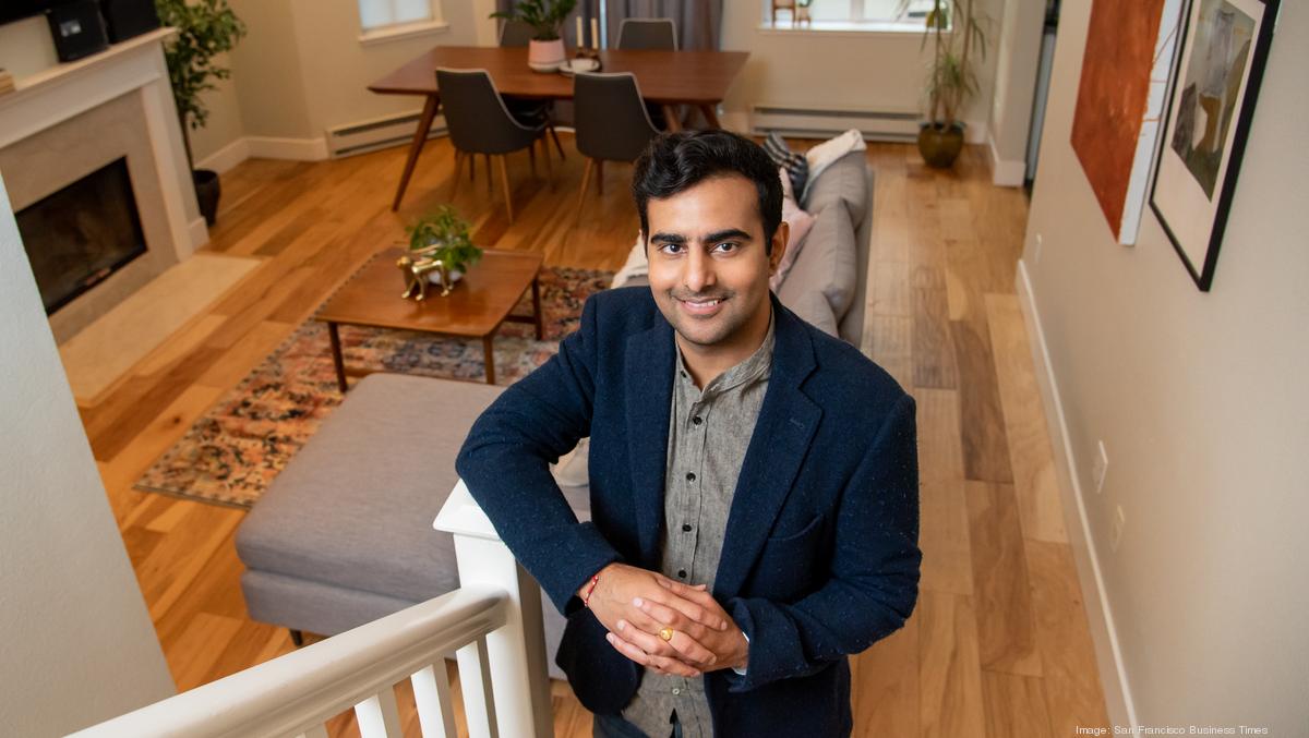Kulveer Taggar beside a staircase in a furnished living and dining space