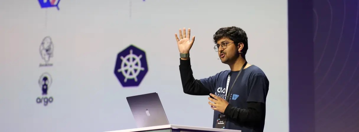 Kunal Kushwaha speaking at a conference podium in front of a presentation on cloud-native technology