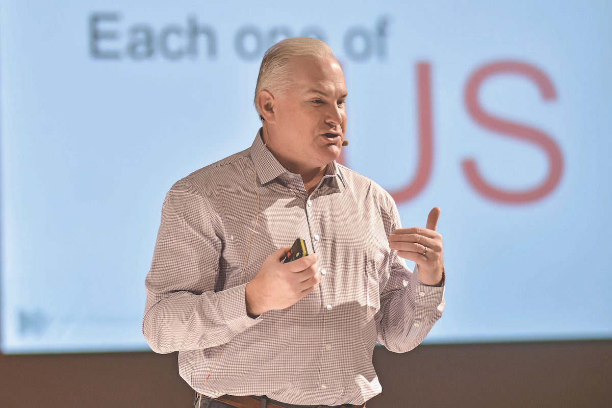 Kurt Ekert speaking onstage during his time leading CWT, holding a presentation remote