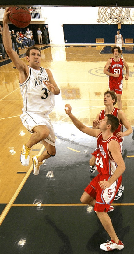 Kyle Beste, wearing Carleton's number 31, goes up toward the basket against Saint John's defenders