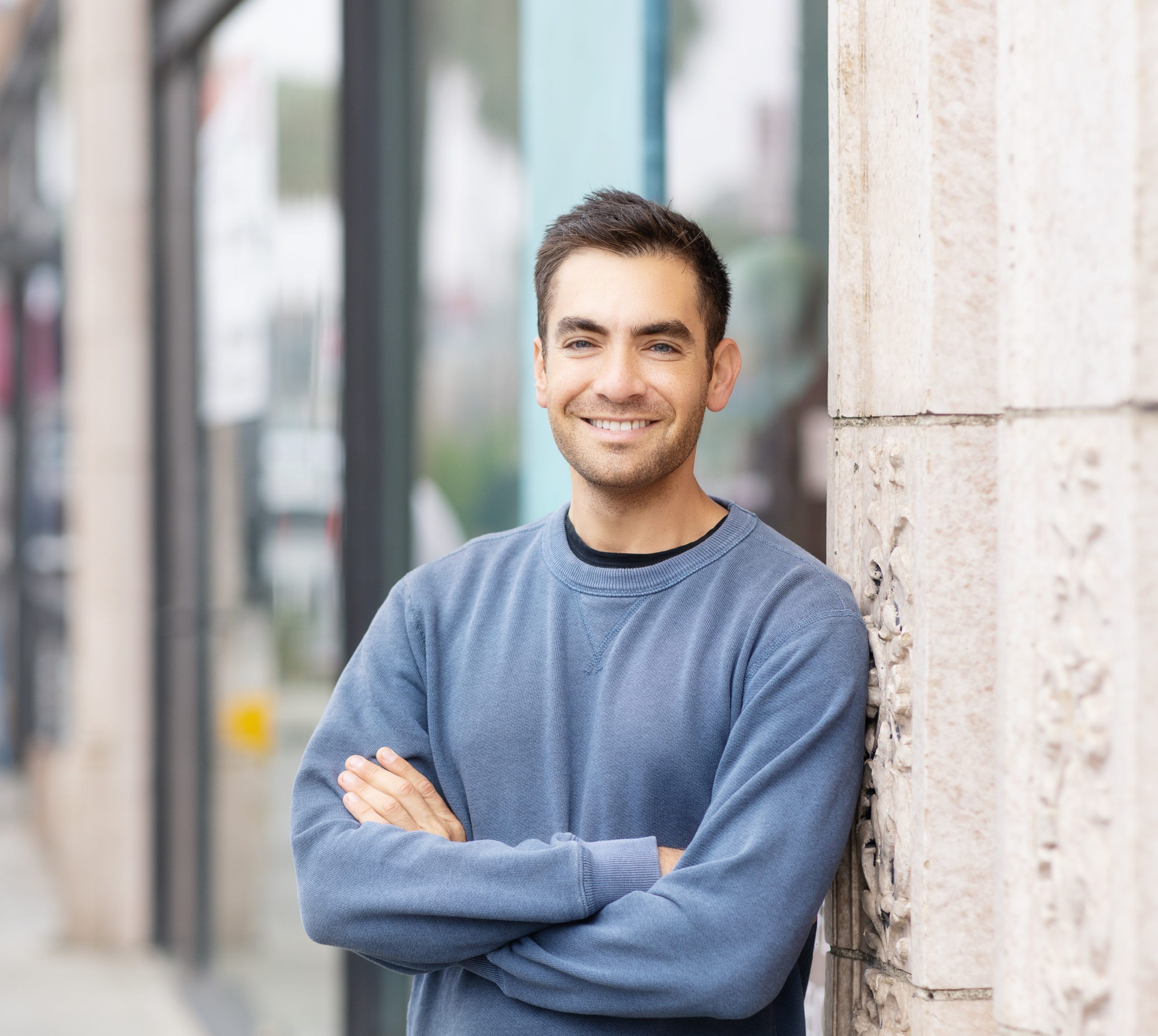 Kyle Michelson in a blue sweater, standing beside a stone wall
