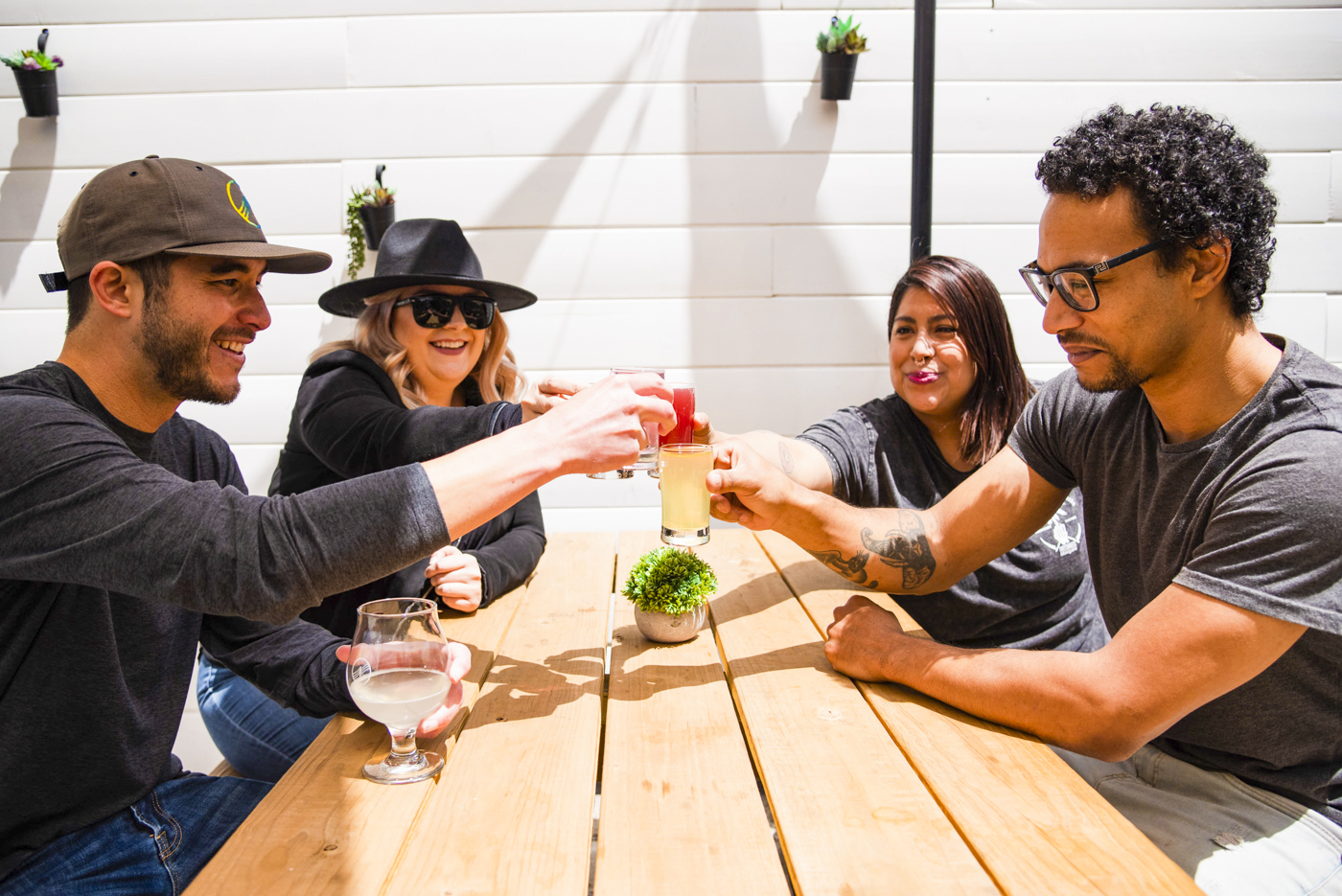 Four guests raise tasting glasses around an outdoor table