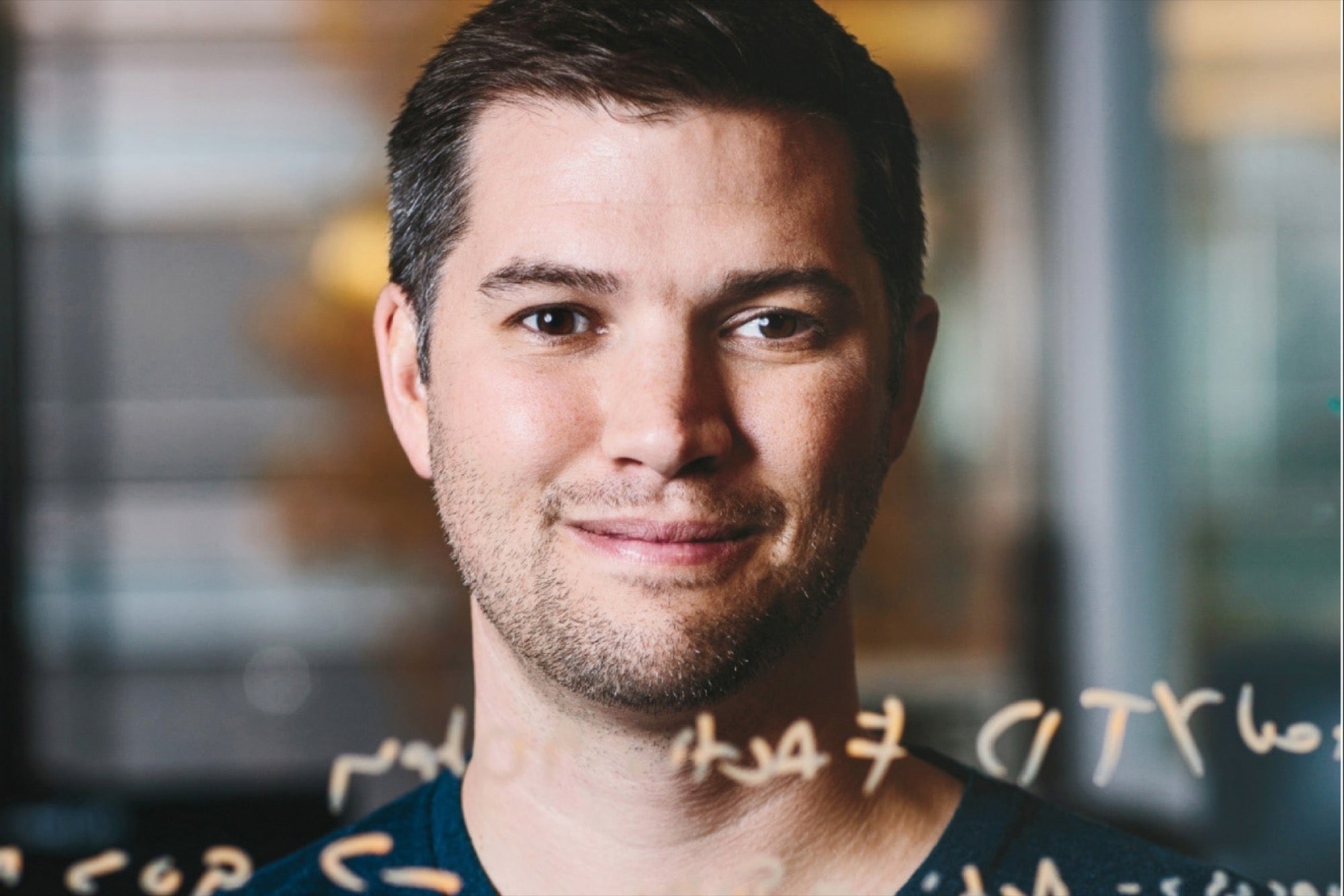 Kyle Porter behind a glass pane covered in handwritten notes, photographed for Entrepreneur