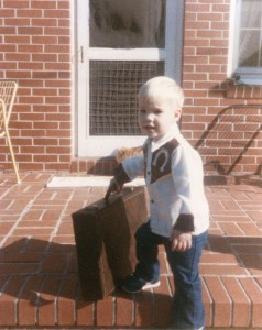 A childhood photograph of Kyle Porter holding a briefcase on a brick porch
