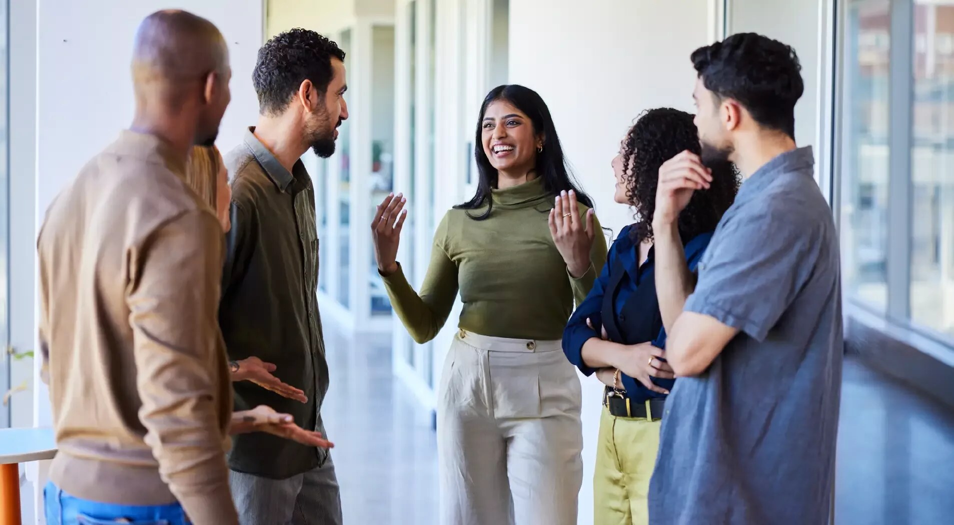 A group of professionals talking in a bright office corridor