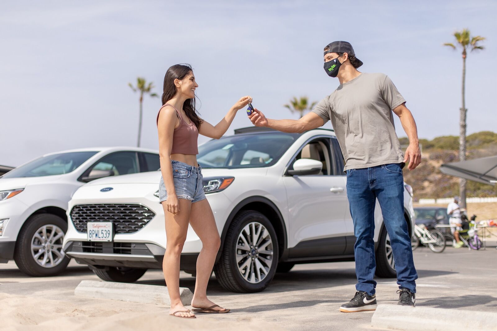 A Kyte delivery partner hands a white rental car to a customer