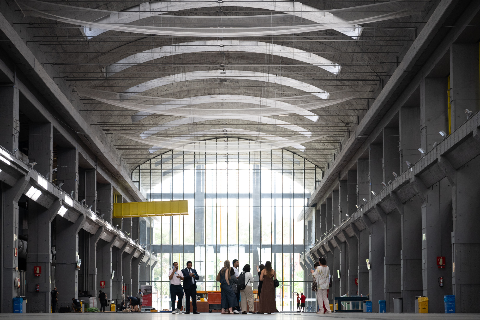 Visitors talking beneath the concrete arches of La Nave’s former industrial hall